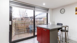 A kitchen with a sliding glass door, a red cabinet, a bar stool, and a clock on the wall. - Zoutleeuw Home With Pool (Zoutleeuw)