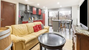 A modern living room with a sofa, a coffee table, and a kitchen area with cabinets and a dining table. - Zoutleeuw Home With Pool (Zoutleeuw)