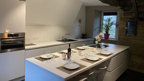 Et moderne køkken med en central ø, indbygget ovn og et vindue med en plante.