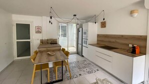 A modern kitchen with a wooden dining table, white cabinets, and a built-in oven. - Kay Agapi - on the beach - Diamant (Le Diamant)