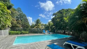 A swimming pool with lounge chairs, surrounded by greenery and a clear sky. - Kay Agapi - on the beach - Diamant (Le Diamant)