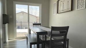 A dining area with a table and chairs, a ceiling light, and decorative wall art. - Ray's Place (Roy)
