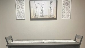 A dining table with benches, a patterned tablecloth, and decorative wall art. - Ray's Place (Roy)