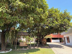 A courtyard with a wooden bench, a hanging chair, and a building entrance. - La Mar Hotel Playas (Playas)