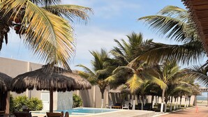 A resort with thatched-roof structures, a swimming pool, and palm trees.