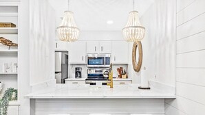 A modern kitchen with white cabinetry, a central island with stools, a microwave, and a coffee machine. - Luxury Townhouse in Santa Rosa Beach - The Zen Pad (Santa Rosa Beach)