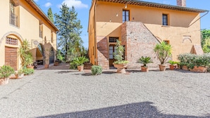 Un patio con suelo de grava, rodeado de edificios con muros de terracota y arcos.
