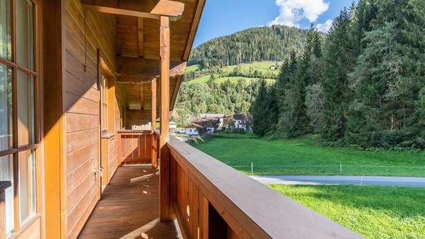 A wooden cabin with a balcony overlooking a green valley and forested hills. - Apartment in Mittersill Near Ski Slopes (Mittersill)