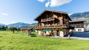 A traditional wooden chalet with a balcony, surrounded by a lush green field and mountains in the background. - Apartment in Mittersill Near Ski Slopes (Mittersill)