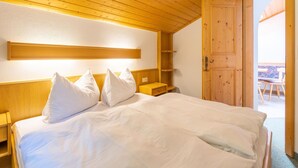 A wooden-paneled bedroom with a bed, bedside tables, and a wooden wardrobe. - Apartment in Mittersill Near Ski Slopes (Mittersill)