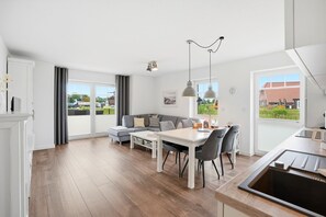 Une cuisine moderne avec un coin repas, de grandes fenêtres et une vue sur l’extérieur.