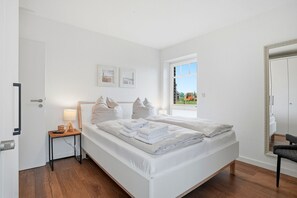 Une chambre à coucher avec un lit, une table de chevet, une lampe et une fenêtre donnant sur l’extérieur.