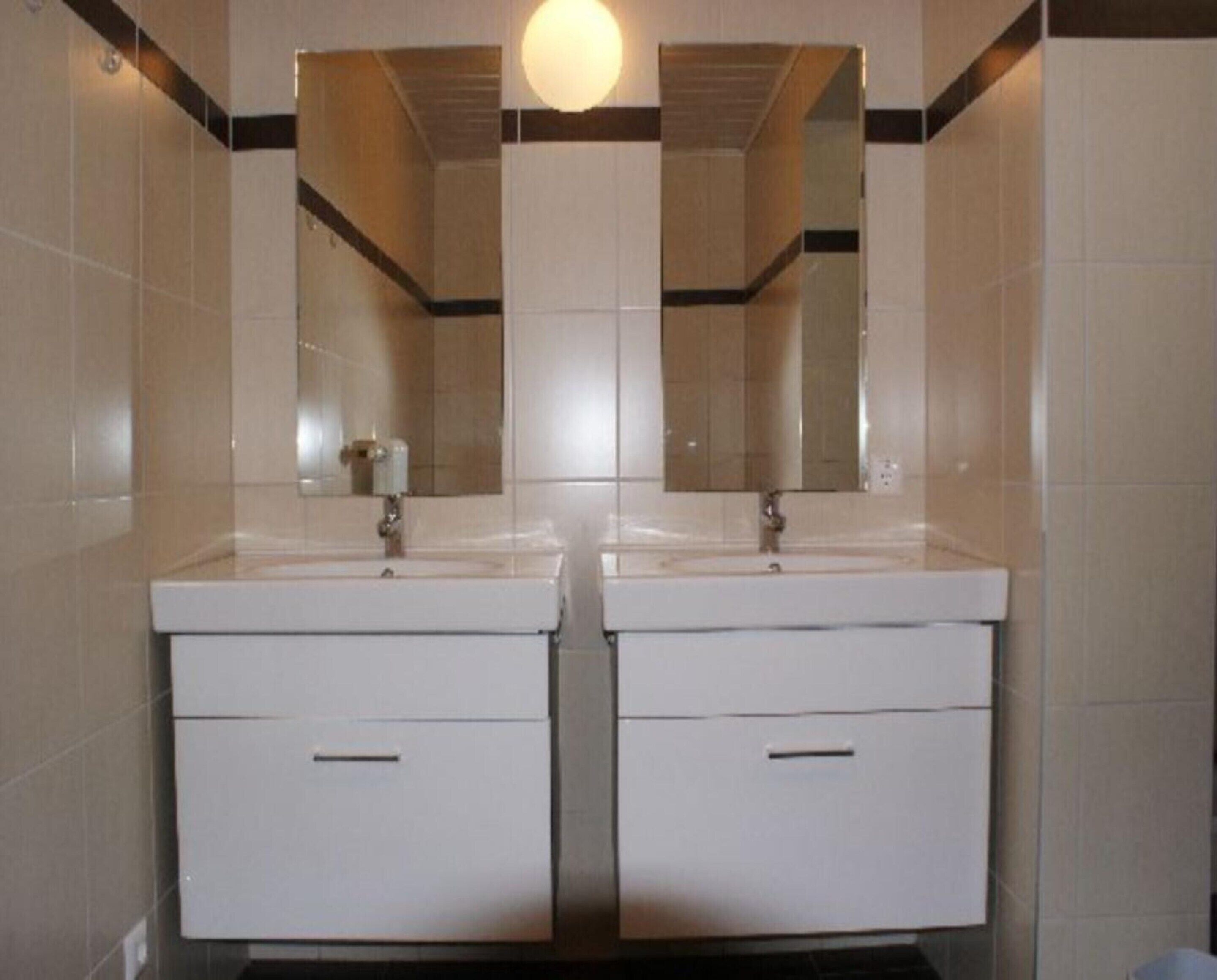 A bathroom with two sinks, each with a mirror above.