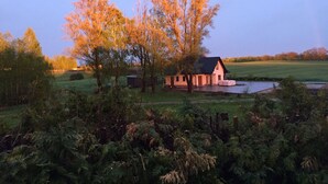 Een landhuis met een vijver, omringd door bomen en groen.