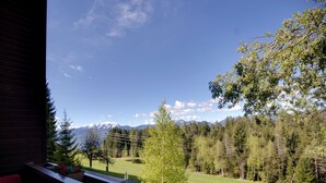 Blick von einem Balkon auf eine gebirgige Landschaft bei klarem Himmel.
