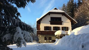 Eine zweistöckige Chalet mit geneigtem Dach, Holzwand und einem Balkon.