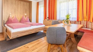 A room with a bed, a dining table, and a sofa. - Elegant Apartment Near the ski bus (Saalbach-Hinterglemm)