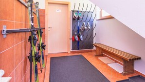 A ski rental area with skis and ski boots on racks, a wooden bench, and a door labeled "PRIVAT". - Elegant Apartment Near the ski bus (Saalbach-Hinterglemm)