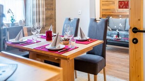 A dining area with a wooden table set for two, equipped with plates, glasses, and napkins.