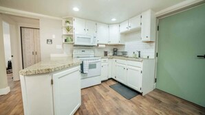 A modern kitchen with white cabinets, a granite countertop, a microwave, and a stove.