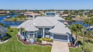 Une grande maison moderne dotée d’un vaste jardin à l’avant, d’un garage et offrant une vue sur un lac.