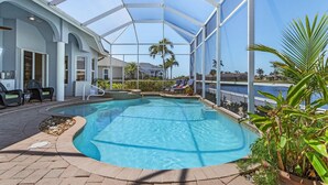 Une piscine couverte avec des chaises longues et une vue sur des palmiers et un bâtiment en arrière-plan.