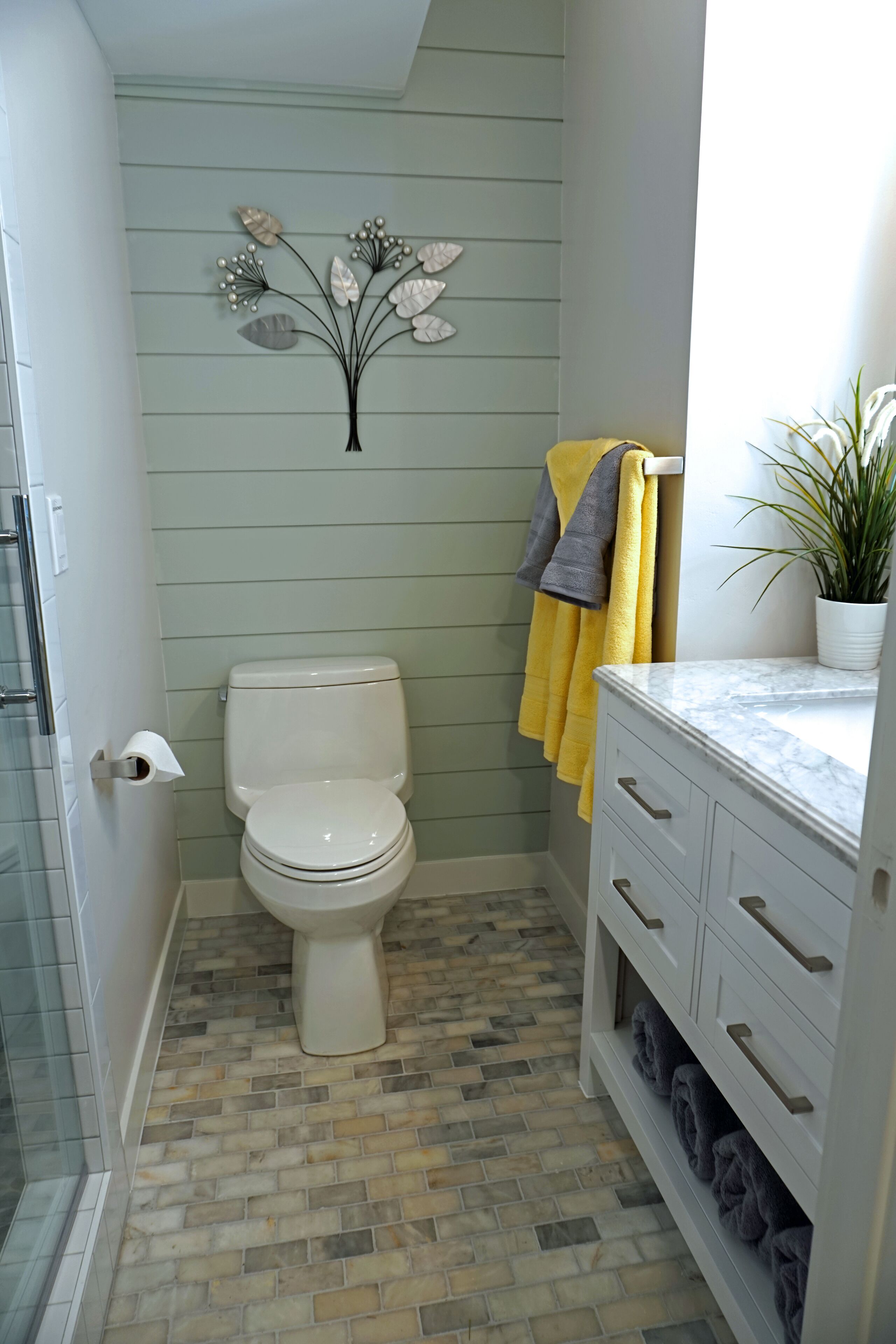 A bathroom with a toilet, a shower, a sink, and a decorative wall piece.