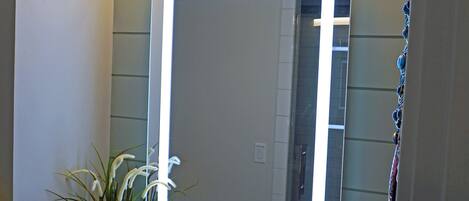 A bathroom with a large mirror, a sink, and a potted plant.