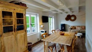 A dining area with a wooden table and chairs, a wooden cabinet with glass doors, and a television on the wall. - Cozy Holiday Home in Nieuwpoort With Swimming Pool (Nieuwpoort)