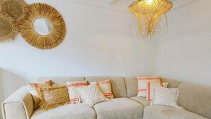 A modern living room with a beige sectional sofa, decorative pillows, a round mirror, and two hanging light fixtures. - Cozy Holiday Home in Nieuwpoort With Swimming Pool (Nieuwpoort)
