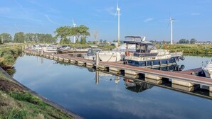 A marina with boats docked, a bridge, and wind turbines in the background. - Cozy Holiday Home in Nieuwpoort With Swimming Pool (Nieuwpoort)