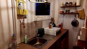 A compact kitchen with a sink, a window, and a shelf with kitchen items. - Tranquil Chalet in Geel With Garden (Geel)