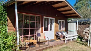 A wooden cabin with a porch, large windows, and outdoor seating. - Tranquil Chalet in Geel With Garden (Geel)