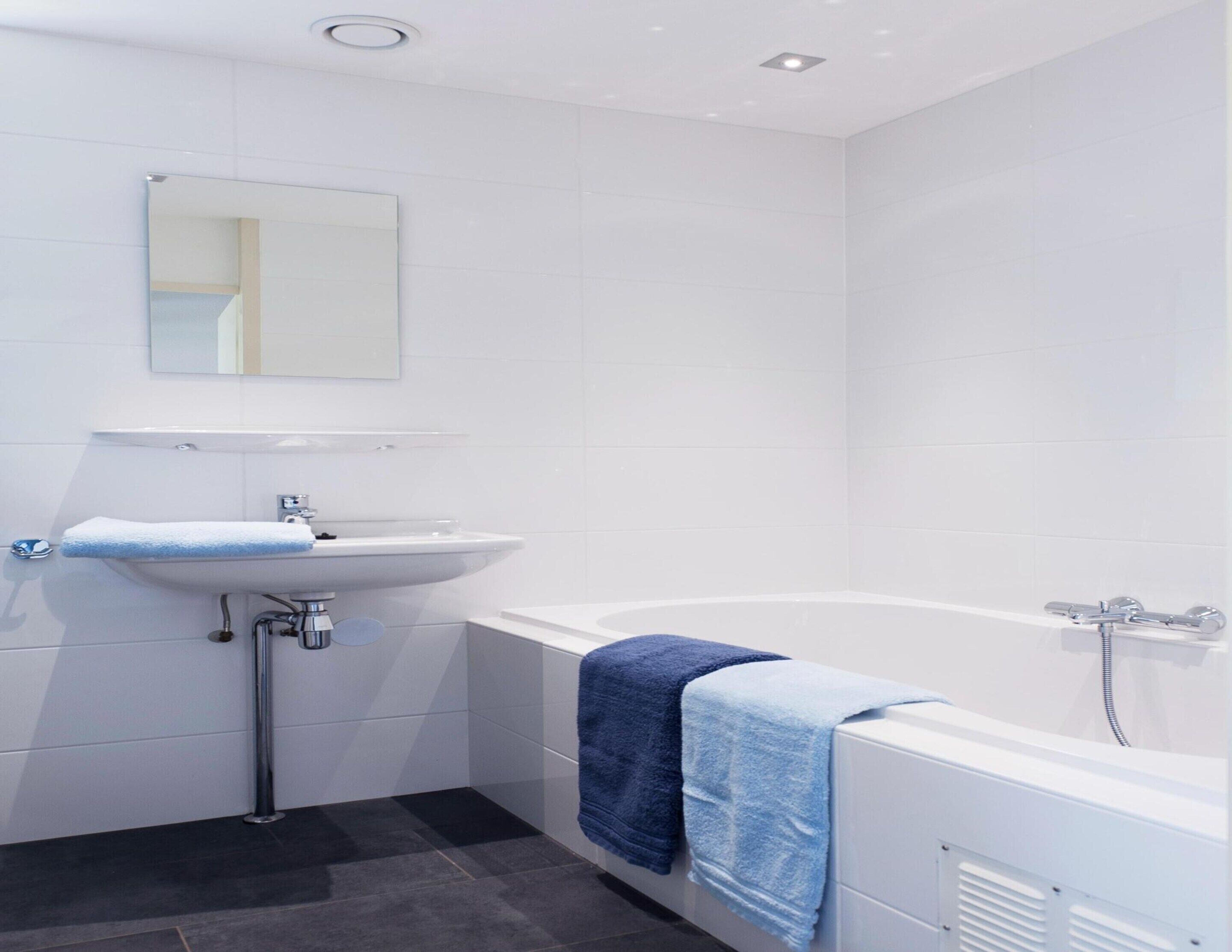 A modern bathroom with a white sink, a mirror, and a bathtub.