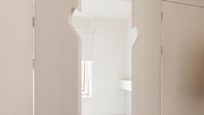 A bedroom with a bed, a window, and a white wardrobe.