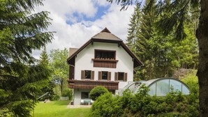 A two-story house with a balcony, surrounded by lush greenery and trees. - Apartment in Mooswald in Carinthia With Pool (Fresach)