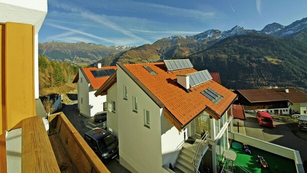 A residential area with houses featuring red-tiled roofs and solar panels, set against a backdrop of mountains and clear skies. - Apartment With Panoramic Views in Fiss (Fiss)