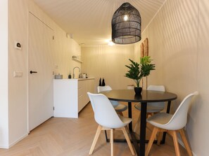 Une cuisine moderne avec des meubles blancs, une table de salle à manger ronde entourée de quatre chaises et un luminaire suspendu.