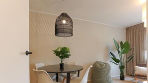 Zona pranzo con tavolo rotondo, due sedie, lampadario e pianta in vaso.
