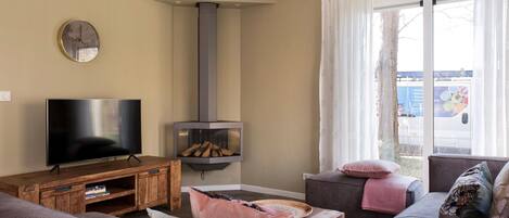 A living room with a flat-screen TV, a fireplace, a sofa, and a window with curtains.