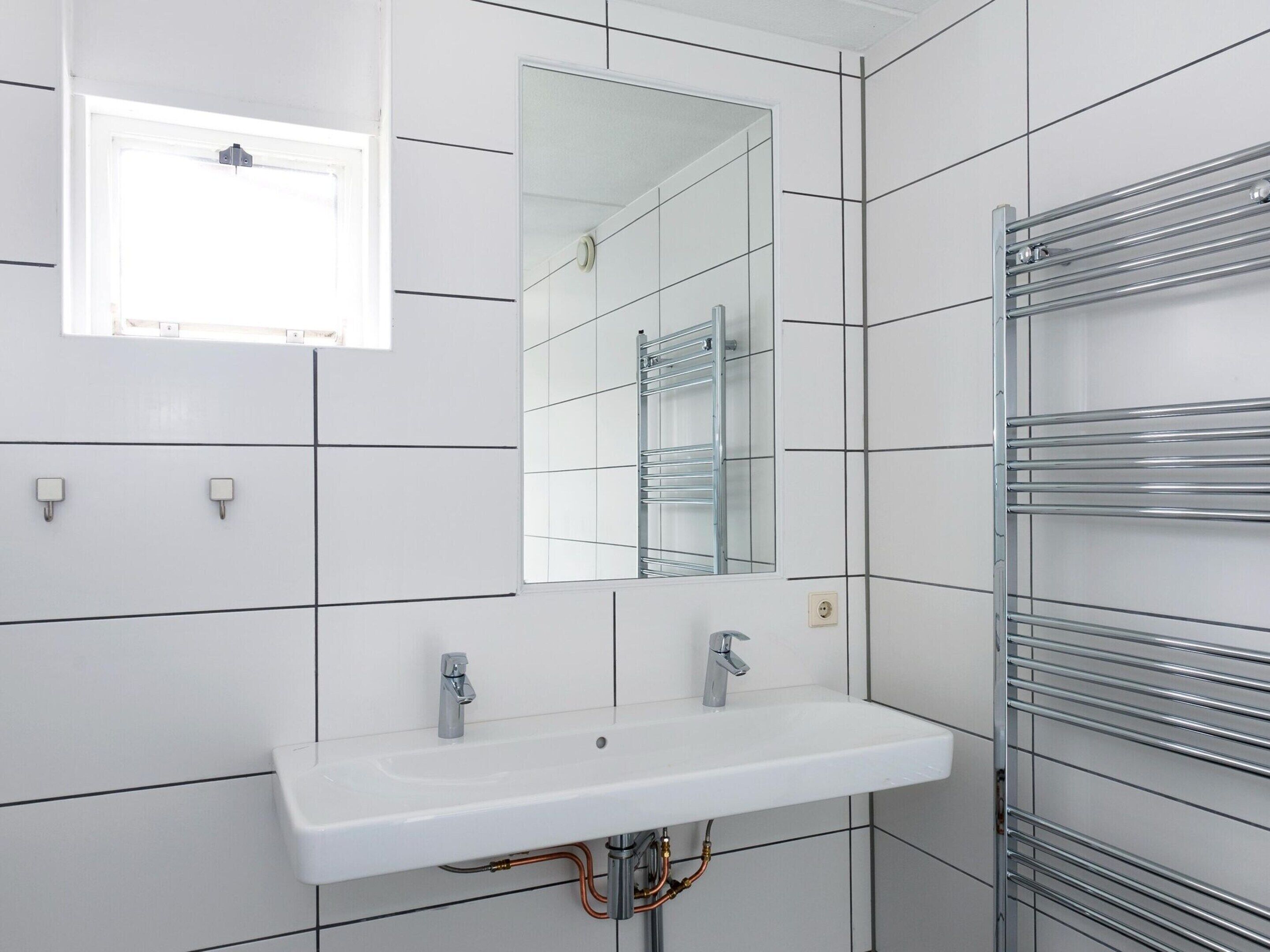 A modern bathroom with a white sink, a mirror, and a towel rack.