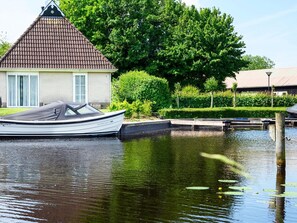 A house with a tiled roof, a dock, and a boat. - Holiday Home With Sauna, Outdoor spa (Earnewald)