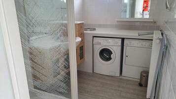 A compact laundry room with a washing machine, dryer, and a small sink.