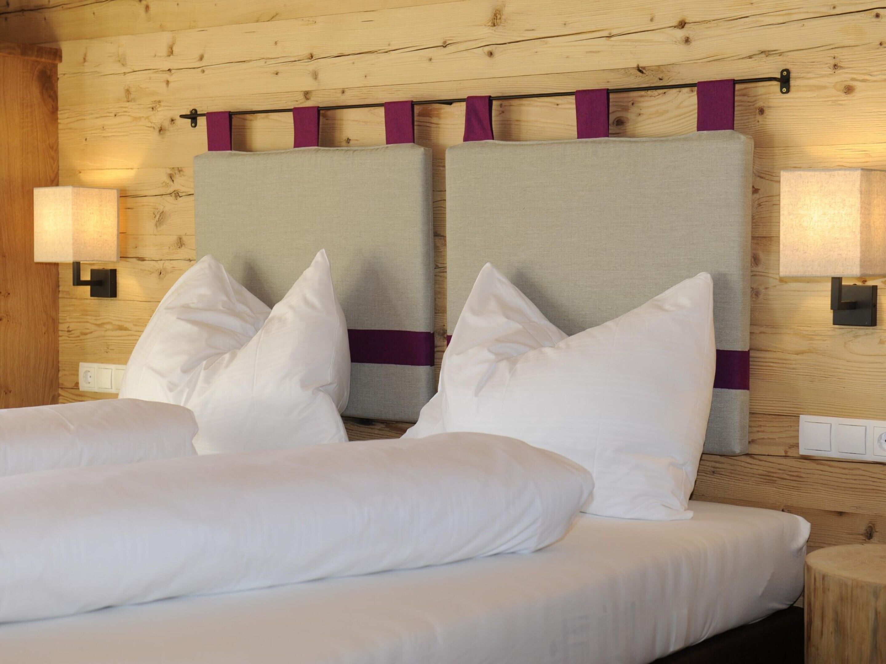A hotel room with a wooden headboard, two bedside tables, and a bed with white bedding.