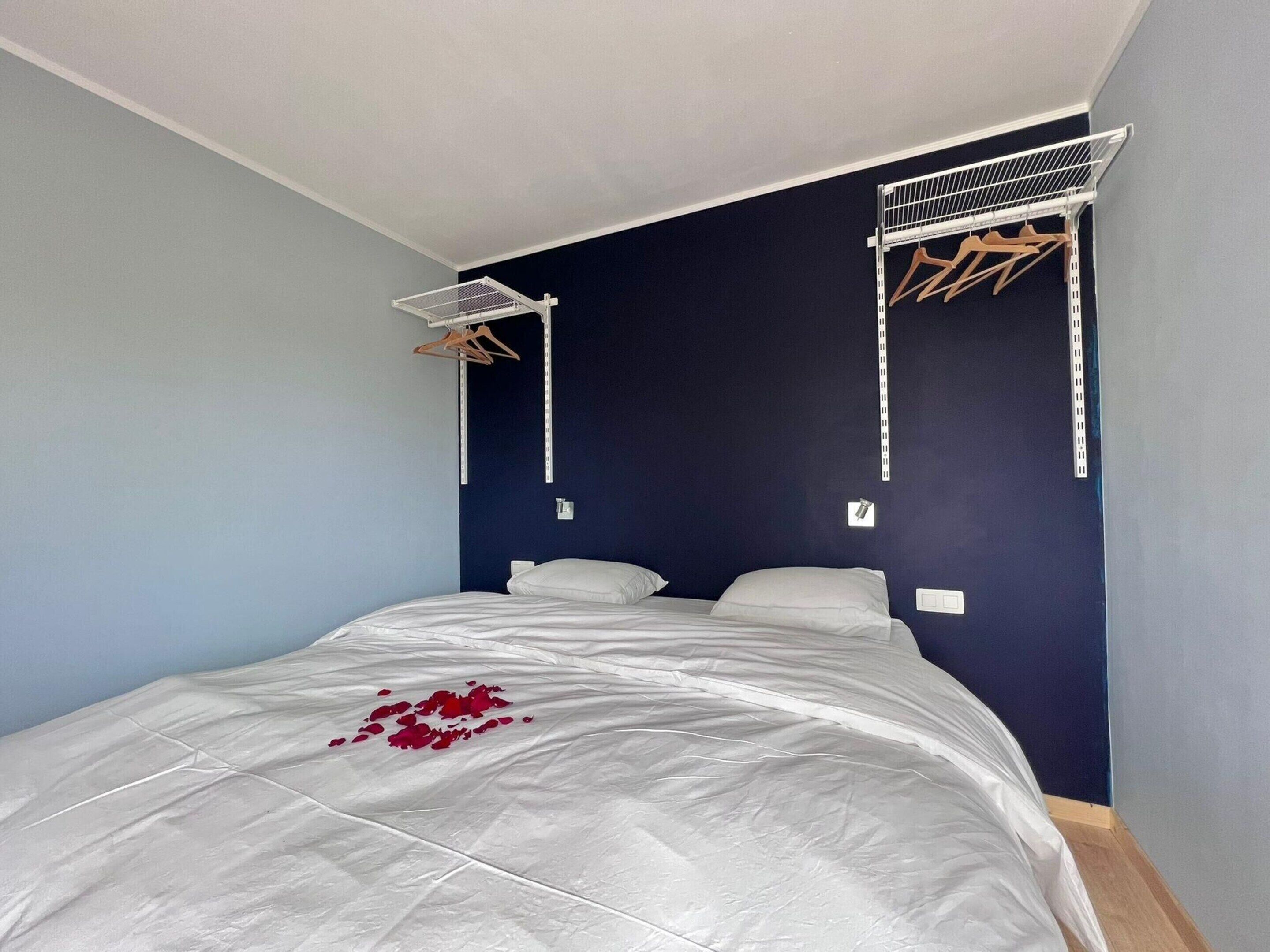 Un dormitorio con cama, tendedero y lámpara de pared.