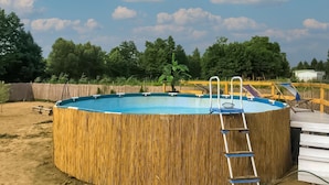 A round above-ground pool with a ladder and a wooden deck. - Holiday Home in Gluszyn With Private Pool (gmina Bytoń)