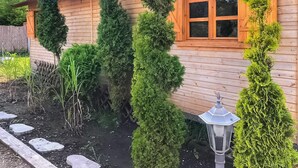 A wooden house with a window and a garden with neatly trimmed bushes. - Holiday Home in Gluszyn With Private Pool (gmina Bytoń)