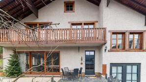 A two-story chalet with a wooden balcony, stone flooring, and a stone fireplace. - Gite in Belgium Near Scenic Hiking Trails (Vresse-sur-Semois)