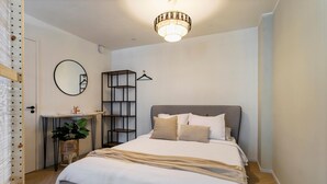A bedroom with a bed, bedside table, mirror, and a hanging light fixture. - Shared Garden Apartment Retreat (Vrouwenpolder)
