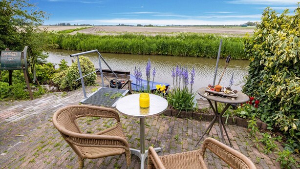 Eine Terrasse mit Korbstühlen, einem kleinen runden Tisch und einer gelben Kerze.